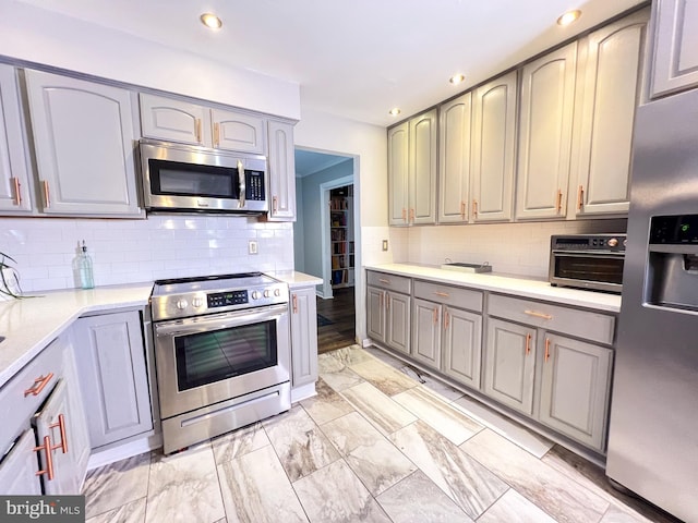 kitchen featuring stainless steel appliances, gray cabinetry, and decorative backsplash