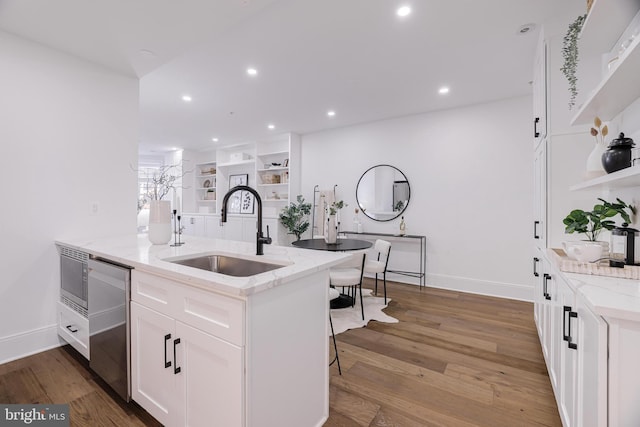 kitchen with sink, light hardwood / wood-style flooring, stainless steel appliances, light stone countertops, and white cabinets