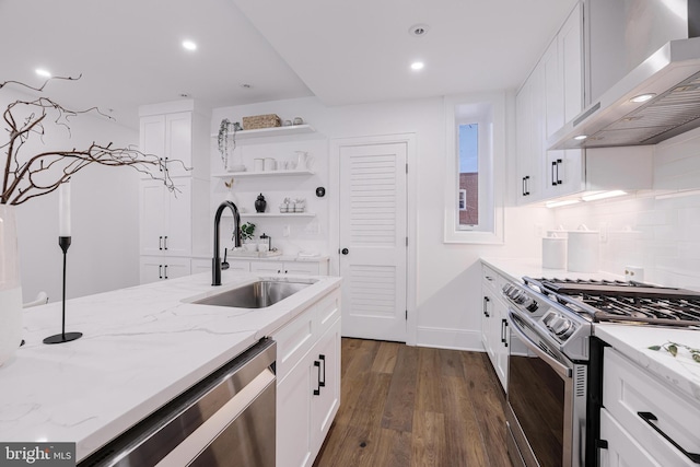 kitchen featuring wall chimney range hood, sink, white cabinets, and appliances with stainless steel finishes