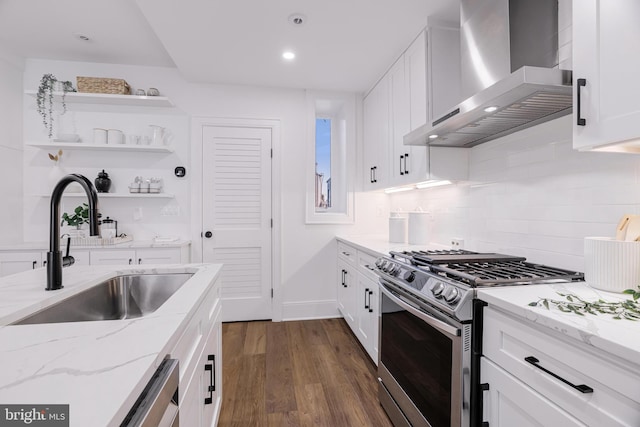 kitchen featuring wall chimney range hood, sink, appliances with stainless steel finishes, light stone counters, and white cabinets