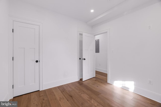 unfurnished bedroom with electric panel and light hardwood / wood-style floors