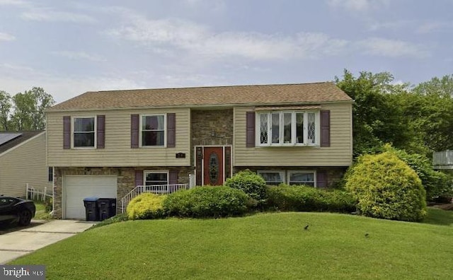 bi-level home featuring a garage and a front lawn