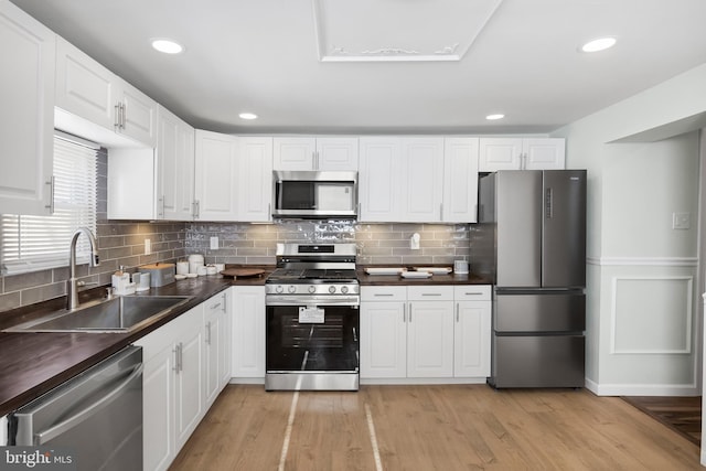 kitchen with white cabinetry, stainless steel appliances, light hardwood / wood-style floors, and sink