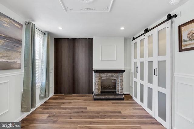 unfurnished living room with a fireplace, a barn door, and hardwood / wood-style floors