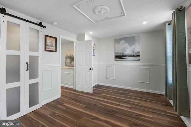 corridor featuring dark wood-type flooring and a barn door