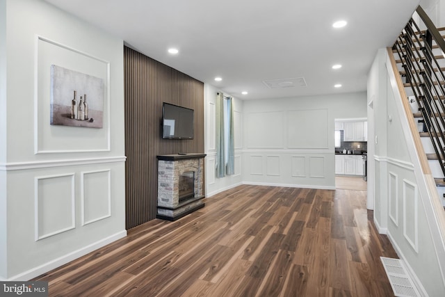 unfurnished living room with a stone fireplace and dark hardwood / wood-style flooring