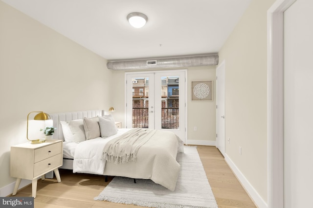 bedroom with access to exterior, light wood-type flooring, and french doors