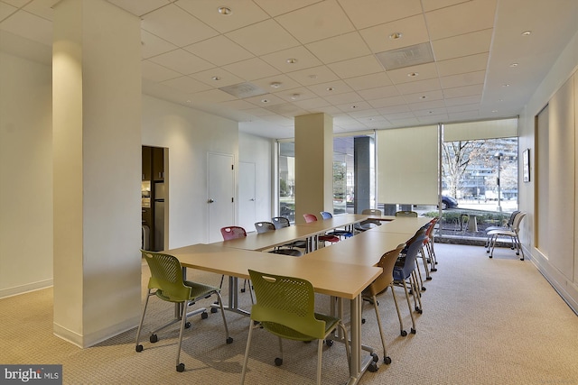 carpeted dining space featuring a drop ceiling and floor to ceiling windows