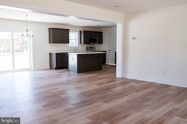 kitchen with a notable chandelier, dark brown cabinets, light hardwood / wood-style floors, and appliances with stainless steel finishes