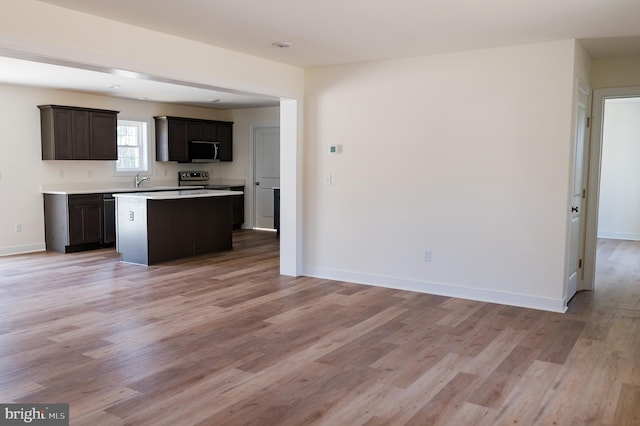 kitchen featuring a kitchen island, light wood-type flooring, sink, and dark brown cabinetry