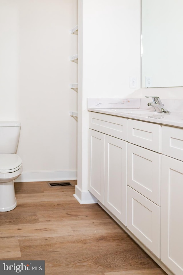 bathroom with wood-type flooring, vanity, and toilet