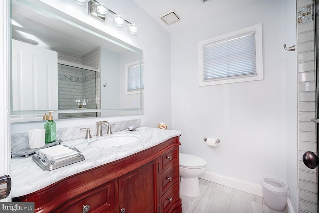 bathroom featuring vanity, toilet, and a shower with door