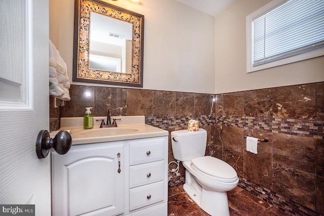 bathroom with vanity, toilet, and tile walls