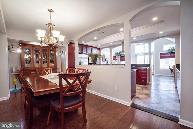 dining area featuring dark wood-type flooring and an inviting chandelier