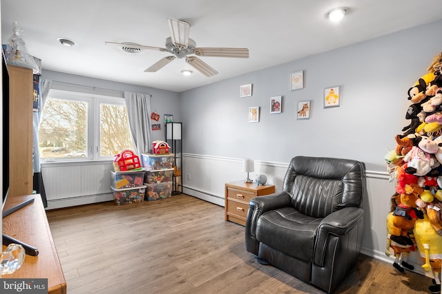 sitting room featuring ceiling fan, baseboard heating, and light hardwood / wood-style floors