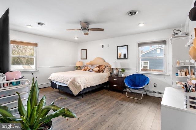 bedroom featuring dark wood-type flooring, ceiling fan, and a baseboard heating unit