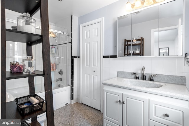 bathroom featuring tiled shower / bath, vanity, and tile walls