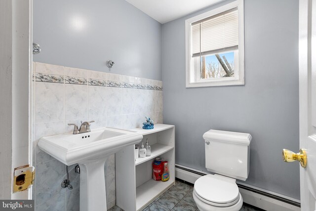 bathroom with a baseboard heating unit, sink, tile walls, and toilet