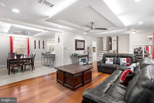 living room featuring a tray ceiling, light hardwood / wood-style flooring, and ceiling fan