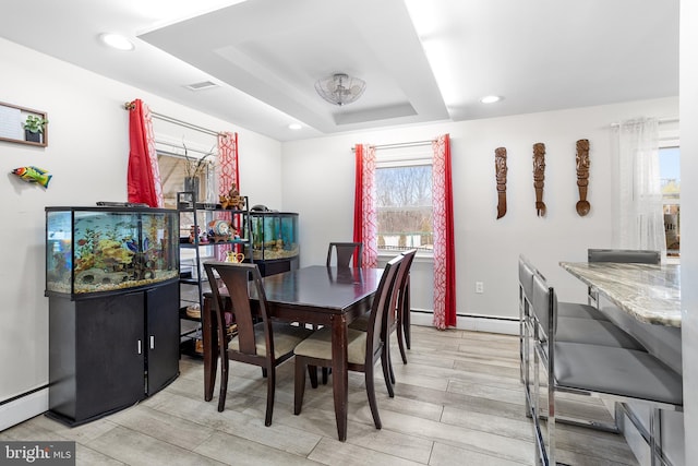 dining space with a raised ceiling and baseboard heating