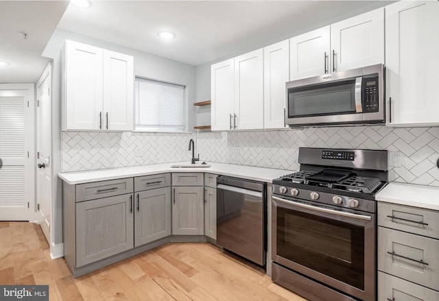 kitchen featuring white cabinetry, stainless steel appliances, gray cabinets, and sink