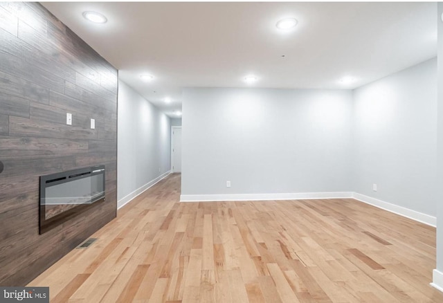 unfurnished living room with wooden walls and light wood-type flooring