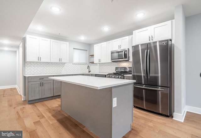 kitchen with stainless steel appliances, white cabinetry, a center island, and light wood-type flooring