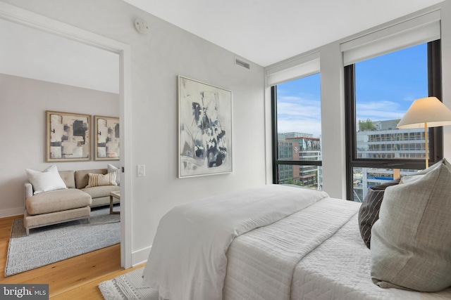 bedroom featuring wood-type flooring and a wall of windows