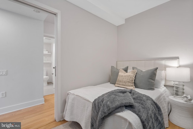 bedroom with wood-type flooring and connected bathroom