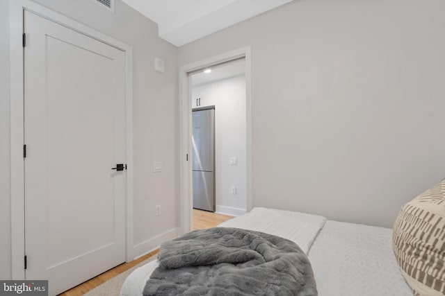 bedroom featuring light hardwood / wood-style flooring and stainless steel refrigerator