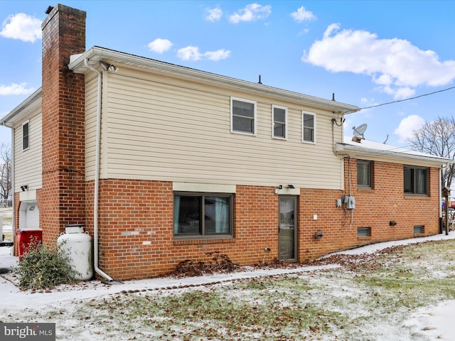 snow covered rear of property featuring a garage