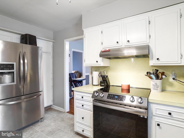 kitchen featuring appliances with stainless steel finishes, light tile patterned floors, and white cabinets