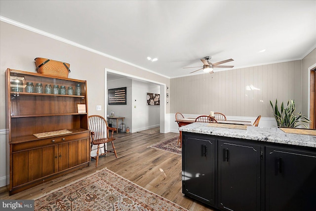 kitchen featuring crown molding, light stone counters, ceiling fan, and light hardwood / wood-style floors