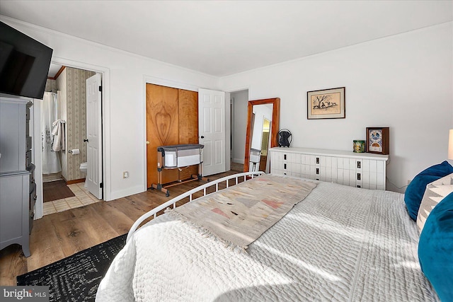 bedroom with connected bathroom and light wood-type flooring