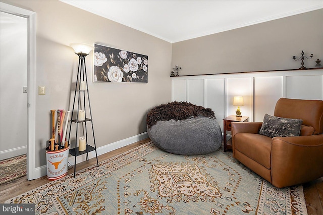 sitting room with hardwood / wood-style flooring and crown molding