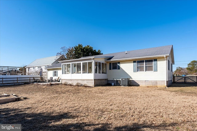 rear view of house with a patio, central AC unit, a sunroom, and a lawn