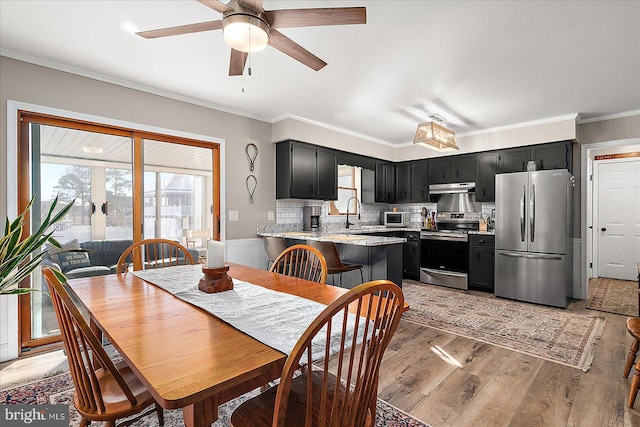 dining space with sink, crown molding, light hardwood / wood-style floors, and ceiling fan