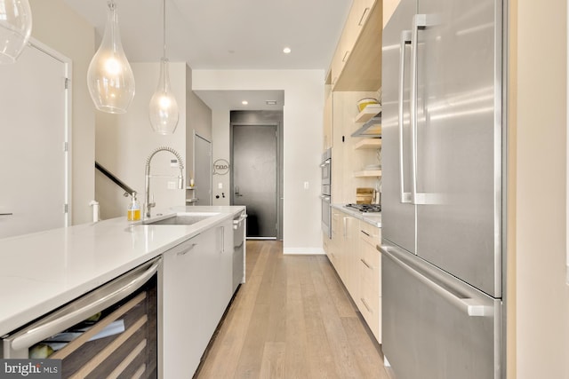 kitchen with sink, appliances with stainless steel finishes, white cabinets, decorative light fixtures, and beverage cooler