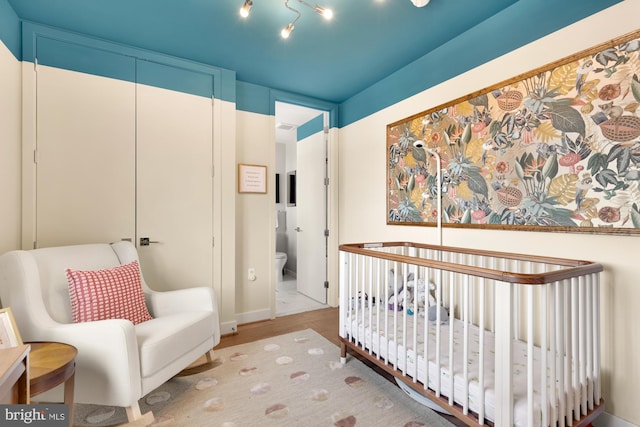 bedroom featuring light hardwood / wood-style floors, a closet, and a crib