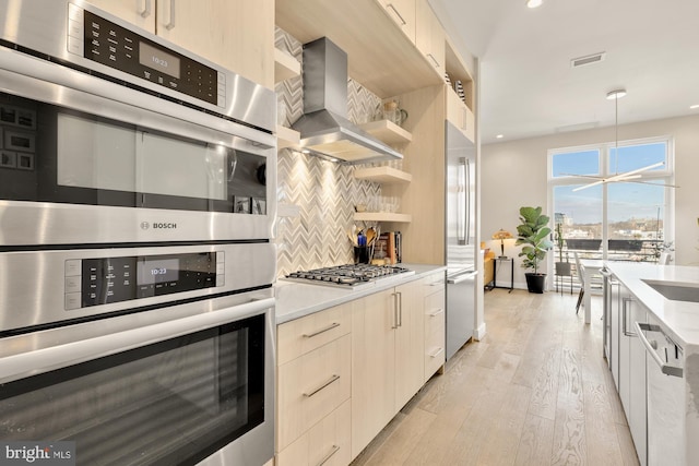 kitchen with extractor fan, decorative backsplash, hanging light fixtures, light hardwood / wood-style floors, and stainless steel appliances