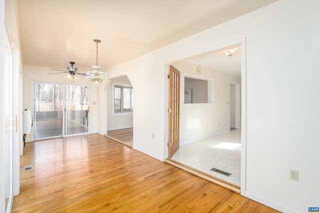 spare room with ceiling fan with notable chandelier and hardwood / wood-style floors