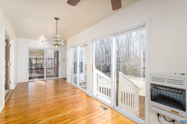 interior space featuring ceiling fan with notable chandelier and heating unit