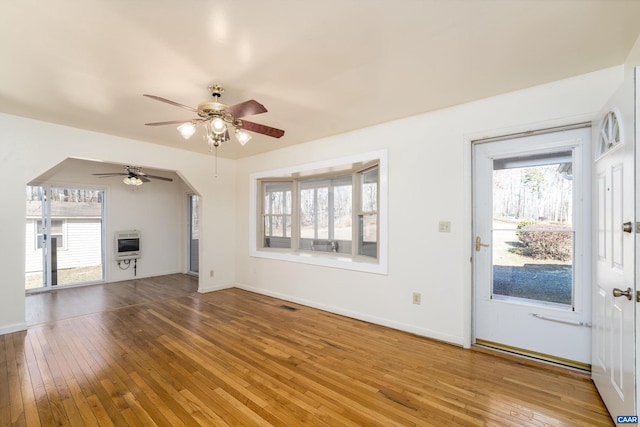 unfurnished living room with ceiling fan, wood-type flooring, and heating unit