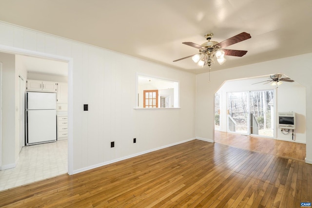 unfurnished living room featuring heating unit, light hardwood / wood-style floors, and ceiling fan