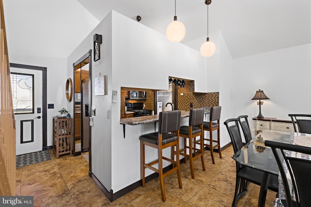 kitchen featuring black gas range oven, a kitchen breakfast bar, tasteful backsplash, white cabinets, and decorative light fixtures