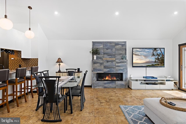 dining space with high vaulted ceiling and a tile fireplace