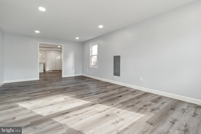 unfurnished room with electric panel and light wood-type flooring