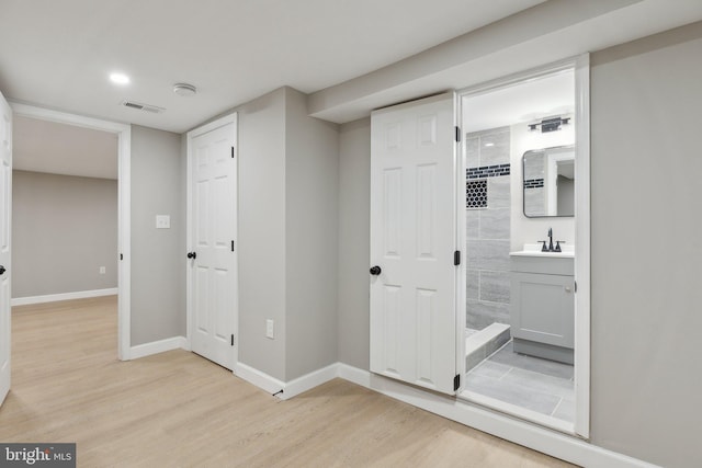 corridor featuring sink and light hardwood / wood-style flooring