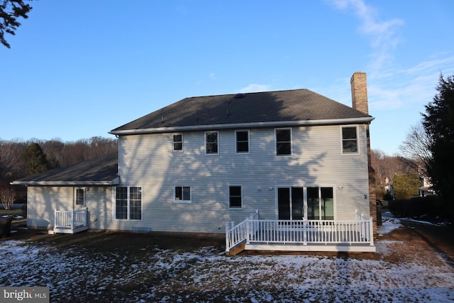 snow covered back of property featuring a wooden deck