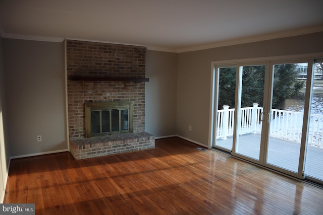 unfurnished living room with a brick fireplace, wood-type flooring, and ornamental molding